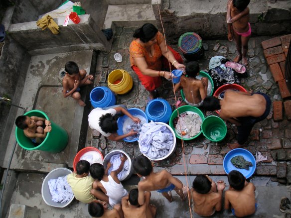 Saving both time and water by washing the children and the clothes at the same time!